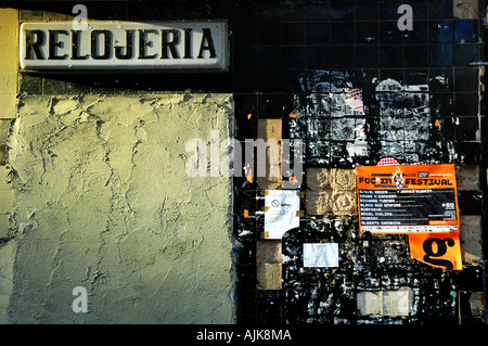 derelict watch and clock shop covered in bill posters lit by early evening light in the city of Valencia Spain Stock Photo