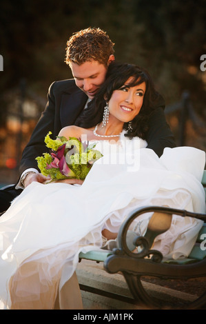 Newly married couple sitting on a bench Stock Photo