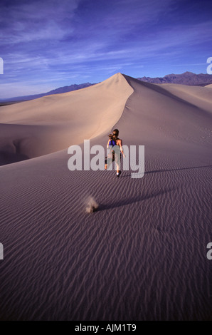 A woman running up a sand dune in Death Valey CA Stock Photo