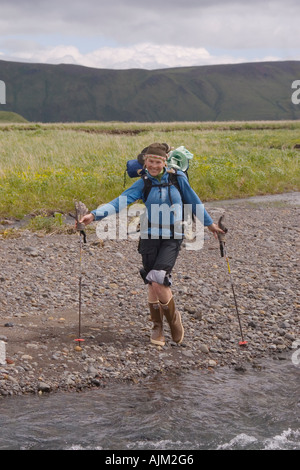 A woman crossing a river on Umnak Island in the Aleutian Islands Stock Photo