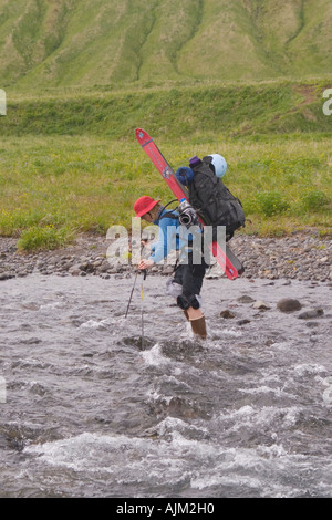 A woman skier crossing a river on Umnak Island in the Aleutian Islands Stock Photo