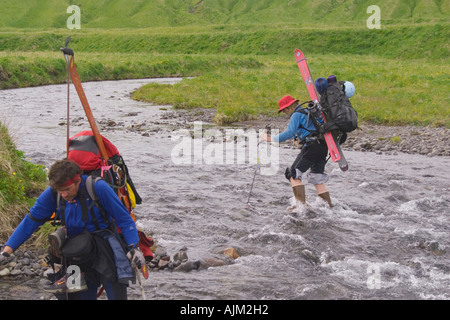 Two skiers crossing a river on Umnak Island in the Aleutian Islands Alaska Stock Photo