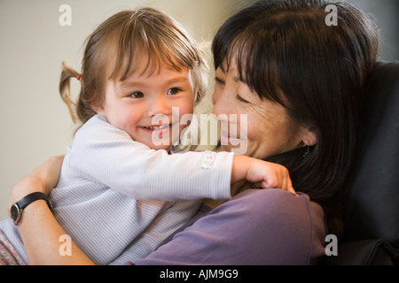 Asian American mother holding her mixed race daughter in her lap Stock Photo