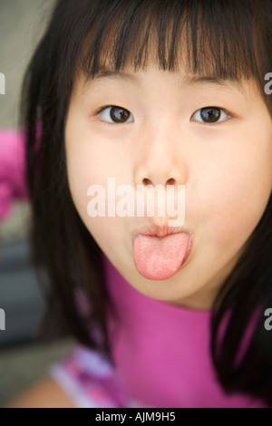 Asian girl sticking out her tongue with humorous expression Stock Photo