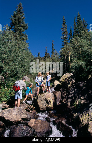 A family of four rock walking off trail in Rocky Mtn Nat l Park CO