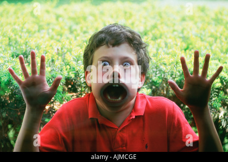 Young boy pressing his face against glass window Stock Photo