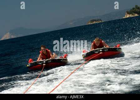 Two boys being towed behind a speedboat on inflatables Skiathos Island Sporades Aegean Sea Mediterranean Greece Luke Hanna Oscar Stock Photo