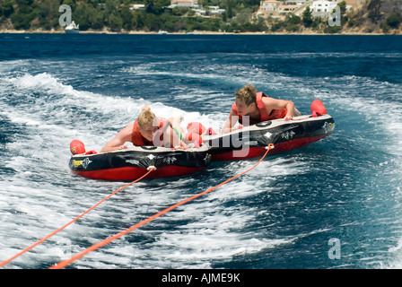 Two boys being towed behind a speedboat on inflatables Skiathos Island Sporades Aegean Sea Mediterranean Greece Luke Hanna Oscar Stock Photo