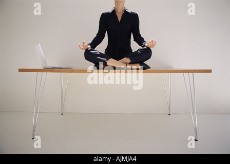 Woman meditating on desk Stock Photo