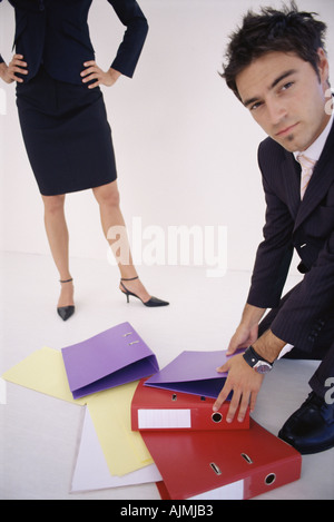 Man picking up folders for woman Stock Photo