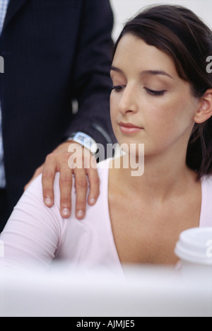 Woman looking at man's hand on her shoulder Stock Photo
