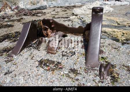 Old cast iron winch from wrecked ship embedded in rocky shingle on rocky shore North Devon UK Stock Photo