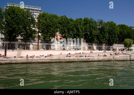 Parisians sunbathing on the banks of the Seine river in Paris. Stock Photo