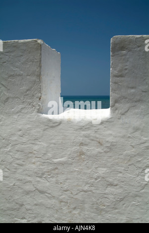 Looking out over the Atlantic Ocean to the horizon through the top of the whitewashed wall of the Medina, Asilah / Arzila Stock Photo