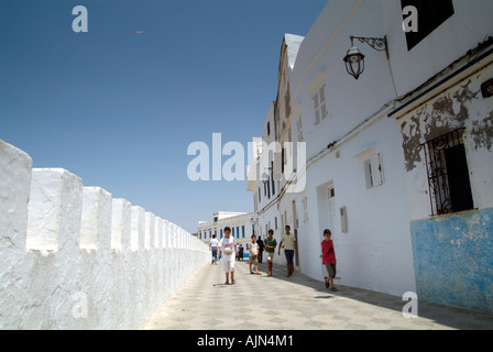 Whitewashed ramparts and houses and children playing in the Medina in Asilah Stock Photo