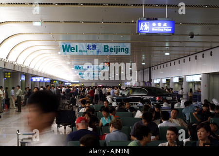 People moving within the main causeway in Beijing's International Airport. Signs welcome visitors to Beijing. Stock Photo