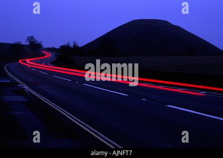 Traffic trails at dusk curving around Silbury Hill on the outskirts of Avebury in Wiltshire county England UK Stock Photo