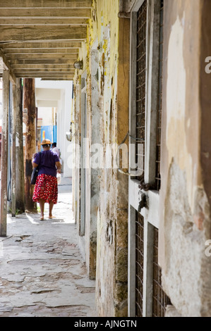 Woman walking on pavement or sidewalk in Speightstown on the Caribbean island of Barbados Stock Photo