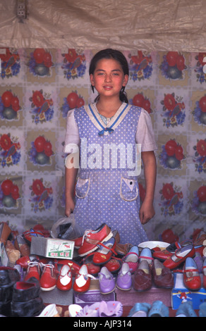 Young Uyghur girl at shoe stall poses for a portrait at Kashgar market China Stock Photo