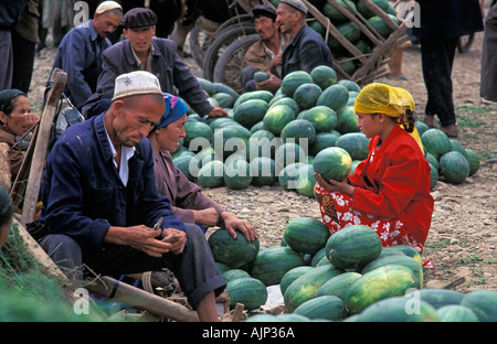 Young muslim girl in bright costume buying a watermelon at Kashgar market Kashgar is at the end of the Karakoram Highway China Stock Photo