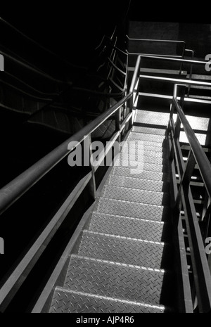 A bright lighted metal stairway leading down Stock Photo