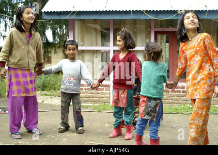 Group Indian children boys girls standing at yard outdoors, holding hands, playing. India. Stock Photo