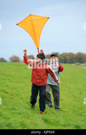 a grandfather and his grandson are flying a kite together Stock Photo