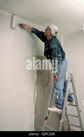 Man on a ladder painting the wall Stock Photo