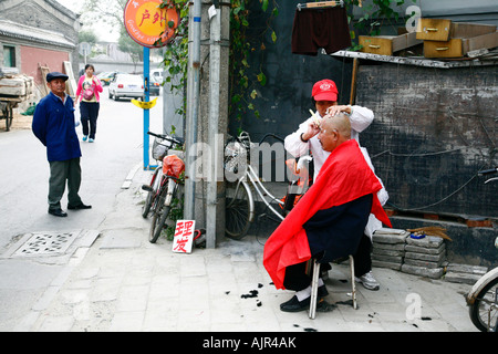 Man getting a hair cut in the street Beijing China Stock Photo