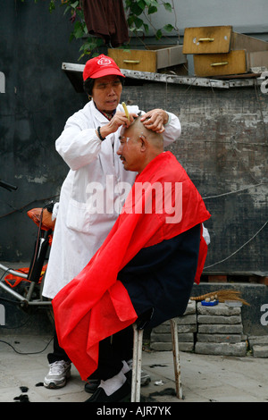 Man getting a hair cut in the street Beijing China Stock Photo