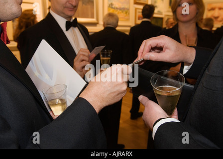 Business cards charity dinner London men exchange contacts address card champagne reception close up handing out contact details. 2000s HOMER SYKES Stock Photo