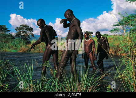 Surma men painting each other as a ritual, west of Omo River Ethiopia. Stock Photo