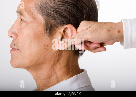 Close-up of a senior woman holding a senior man's ear Stock Photo