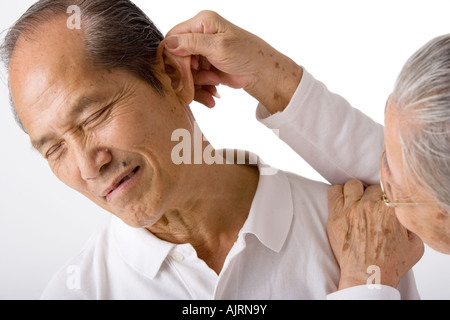 Close-up of a senior woman holding a senior man's ear Stock Photo