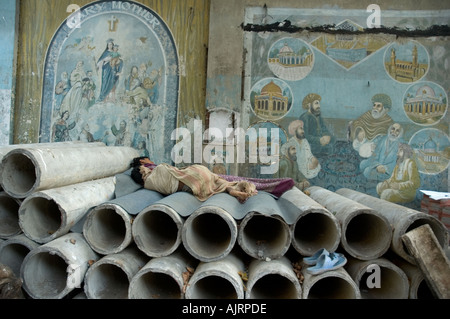 Homeless people sleeping in front of painting describing religious harmony in Mumbai India Stock Photo