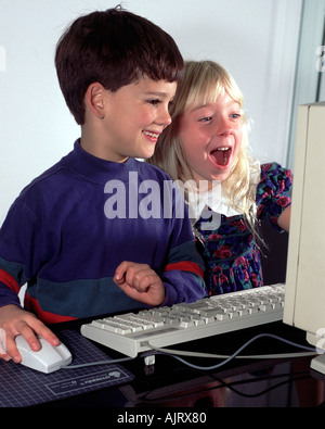 Preteen boy and girl happily play on computer. Stock Photo