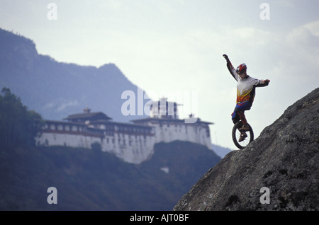 Unicyclist riding down hill with old building in background Stock Photo