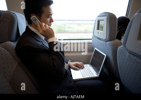 Close-up of a businessman using a laptop and talking on a mobile phone Stock Photo