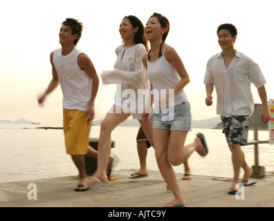 Two young women and two young men running on a pier Stock Photo