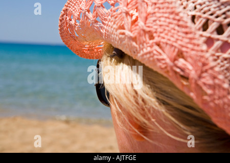 SIDE VIEW OF A WOMANS HEAD WITH HAT AND SUNGLASSES ON A BEACH Stock Photo