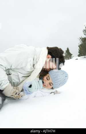 Young couple reclining in the snow, playing around Stock Photo