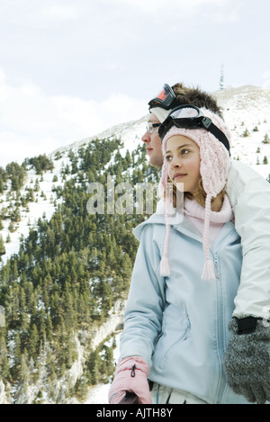 Two young skiers standing together, looking away, one's arm around the other's shoulder Stock Photo