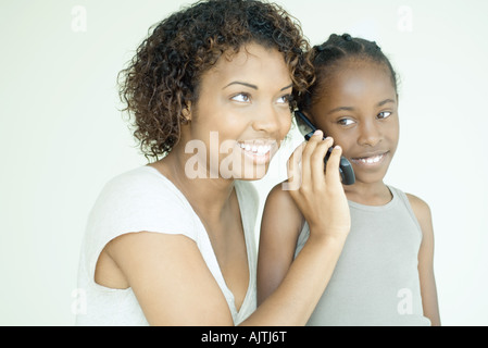 Mother and daughter using cell phone together, smiling Stock Photo
