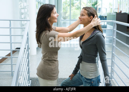 Mother and teenage girl together, woman pushing daughter's hair back, side view Stock Photo