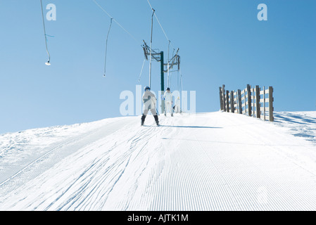 Young skiers going up hill on ski lift, rear view Stock Photo