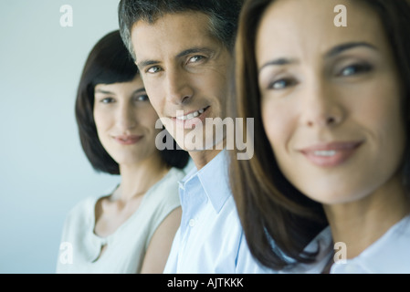 Business team in a row smiling at camera, head and shoulders, focus on man in middle, portrait Stock Photo