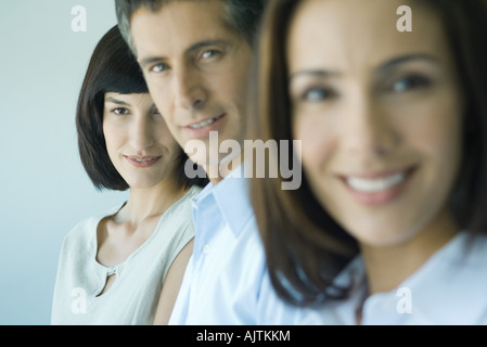 Business team in a row smiling at camera, head and shoulders, focus on woman in background, portrait Stock Photo