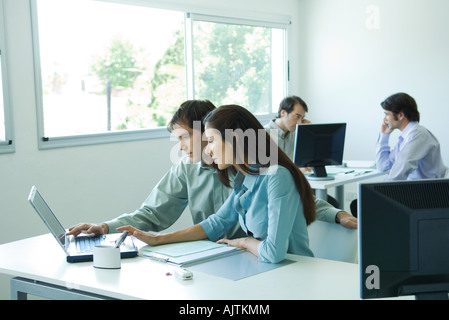 Male and female colleagues working on laptop together Stock Photo