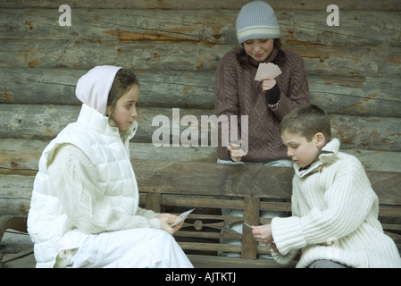 Young friends in winter clothes playing cards Stock Photo