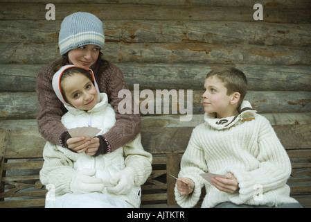 Young friends in winter clothes playing cards Stock Photo
